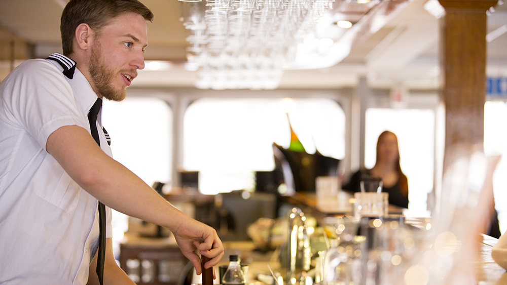A server serving a drink to a customer aboard the AML Louis Jolliet in Quebec City