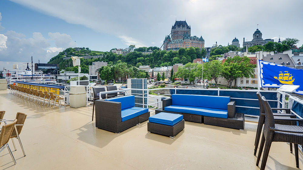 Private rooftop outdoor terrace on the AML Louis Jolliet ship with a view of the panoramic cityscape of Quebec City in the background