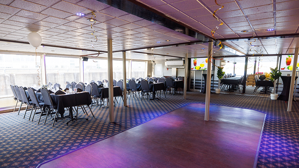  Indoor room with set tables on the left side and a dance floor in the center.