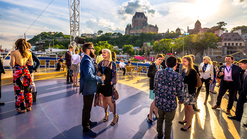 A group of people enjoying one of the outdoor terraces of the AML Louis Jolliet ship with a stunning view of Quebec City and the Château Frontenac