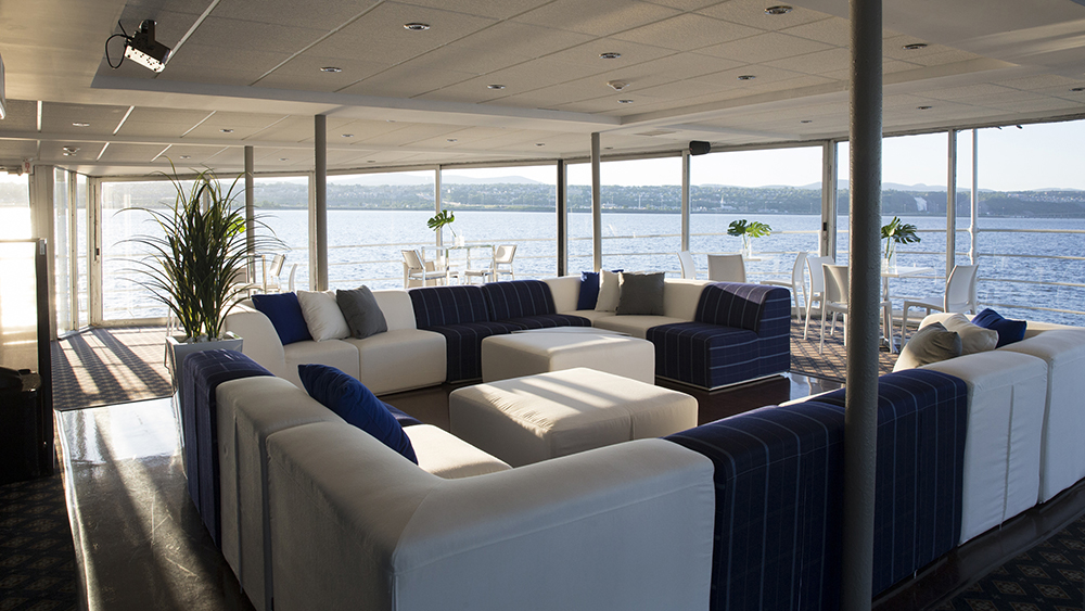 Private lounge furnished with comfortable sofas and bay windows overlooking the Saint Lawrence River in Quebec