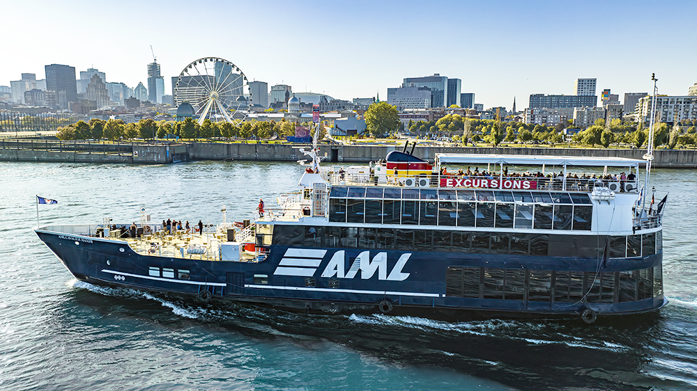 Le navire AML Cavalier Maxim naviguant sur le fleuve Saint-Laurent avec le Vieux-Port et la skyline de Montréal en arrière plan. 