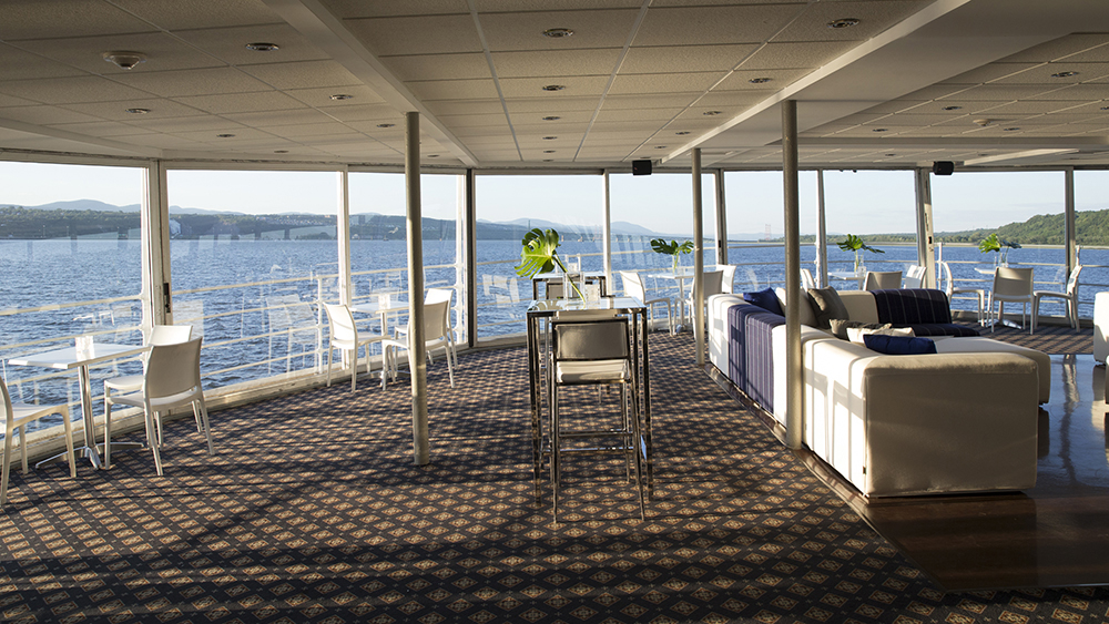 Private lounge furnished with comfortable sofas and bay windows overlooking the Saint Lawrence River in Quebec