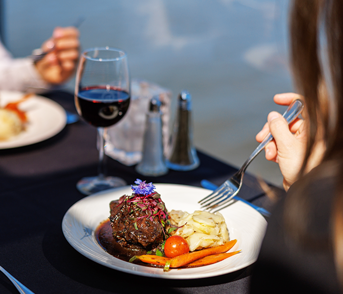 Assiette comprenant un repas bistronomique de viande grillée avec des légumes frais du marché accompagné d'un verre de vin rouge