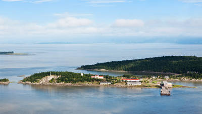 Aerial view of Grosse-Île and the St. Lawrence River. Greenery and buildings typical of the island can be seen.