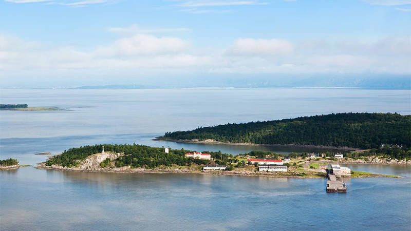 Aerial view of Grosse-Île and the St. Lawrence River. Greenery and buildings typical of the island can be seen.