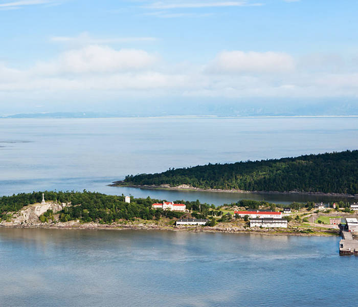 Aerial view of Grosse-Île and the St. Lawrence River. Greenery and buildings typical of the island can be seen.