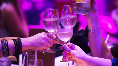 Trois amis trinquant avec des verres de vin blanc dans une ambiance festive en gros plan.