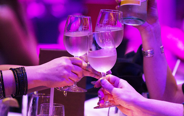Trois amis trinquant avec des verres de vin blanc dans une ambiance festive en gros plan.