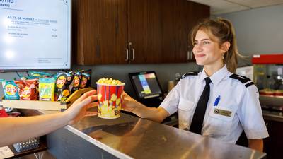 Une serveuse souriante servant du popcorn à un client. Bistro à bord du AML Louis Jolliet à Québec.