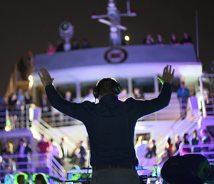 A DJ is hosting an eclectic evening with a crowd dancing on one of the terraces of the AML Cavalier Maxim ship in Montreal