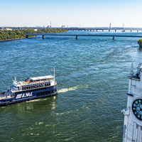 The AML Cavalier Maxim ship sailing on the Saint Lawrence River with the Montreal Clock Tower in the foreground and the Saint Helen's Island and the Samuel de Champlain Bridge in the background