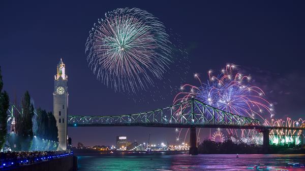 Vue sur la tour de l'horloge et le pont Jacques Cartier à Montréal avec des feux d'artifice majesteux surplombant les monuments
