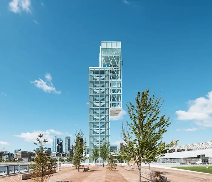 Tour du Port de Montréal avec en premier plan une esplanade arborée et en arrière plan des immeubles de Montréal
