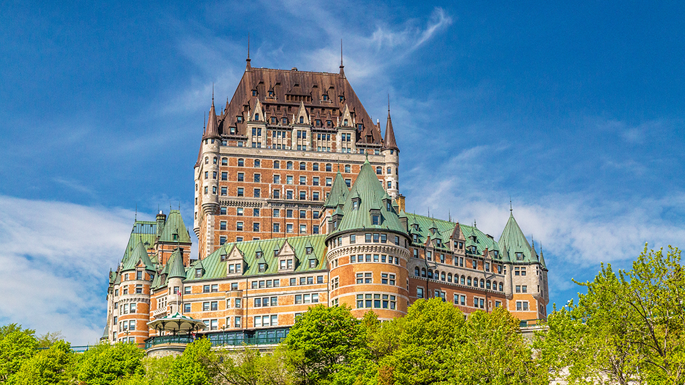Le Château Frontenac de Québec se dressant majestueusement avec un ciel bleu et de la verdure luxuriante.