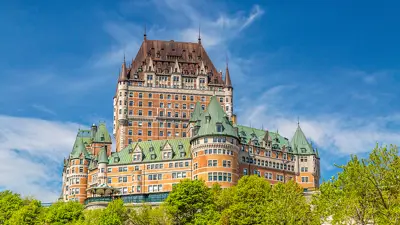 Le Château Frontenac de Québec se dressant majestueusement avec un ciel bleu et de la verdure luxuriante.