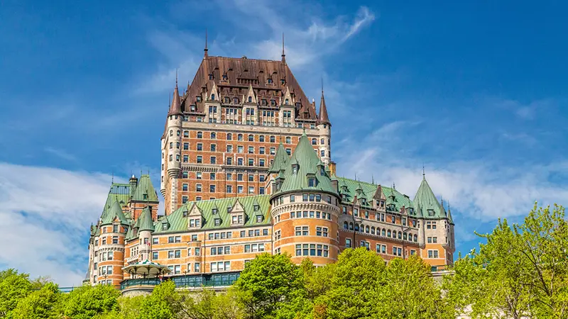 Le Château Frontenac de Québec se dressant majestueusement avec un ciel bleu et de la verdure luxuriante.