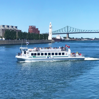 Montreal river shuttle sailing on the Saint Lawrence River with the clock tower and Jacques Cartier Bridge in the background