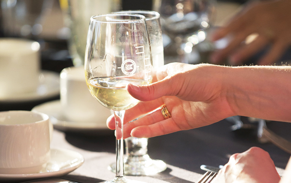  A hand holding a glass of chilled white wine in close-up.