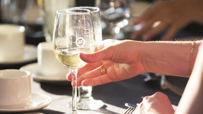  A hand holding a glass of chilled white wine in close-up.