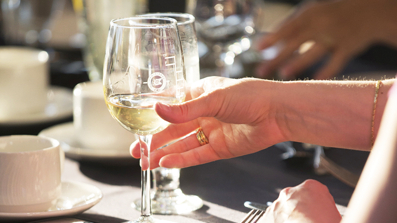 Une main tenant un verre de vin blanc frais en gros plan.