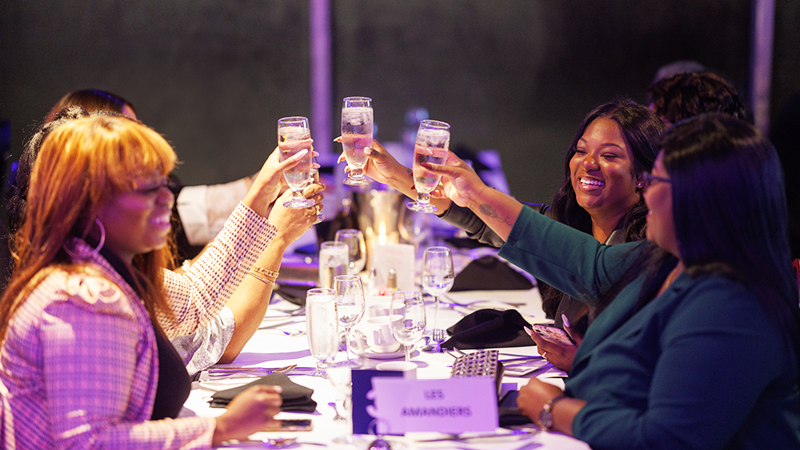 Un groupe de femmes souriantes trinquant avec des coupes de champagne à une table lors d'un souper-croisière à bord du navire AML Cavalier Maxim à Montréal.