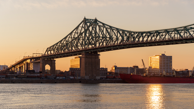 The Jacques Cartier Bridge surrounded by the warm light of a sunset appearing in the background.