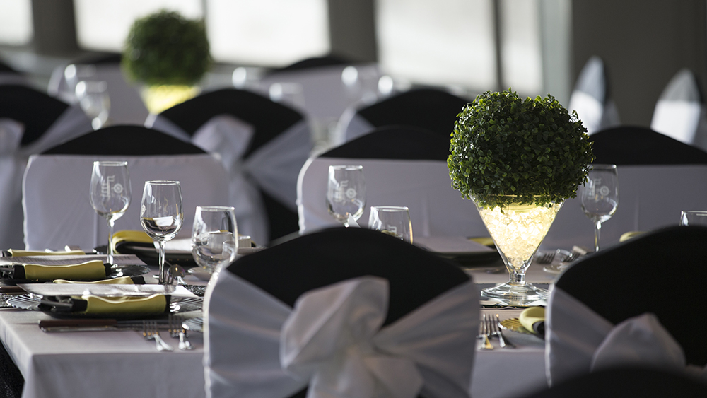 Close-up of the dining room with set and decorated tables. Each table is also adorned with plates, glasses, and folded napkins