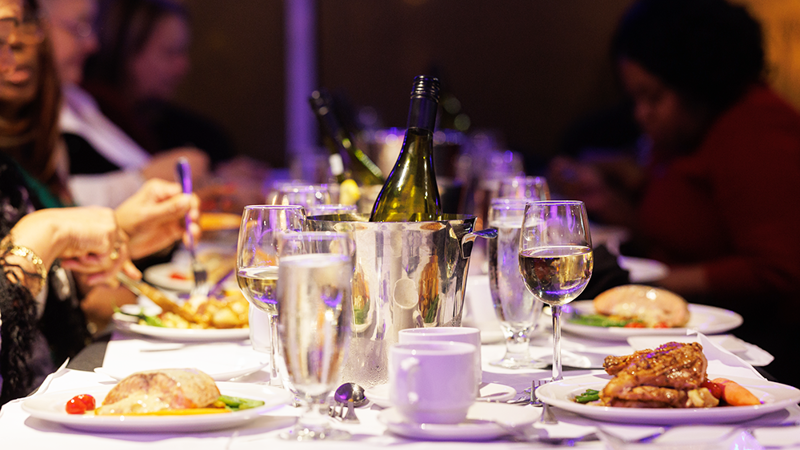 Gros plan sur une table d'un souper-croisière garnie de plats, de verres et de bouteilles de champagne et de vin.
