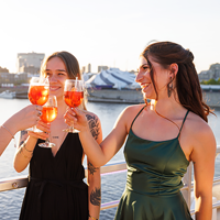 Trois femmes habillées de façon élégante trinquant avec des cocktails sur la terrasse du navire AML Cavalier Maxim à Montréal 
