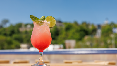 A close-up of a glass of fruity red cocktail placed on a wooden table on one of the terraces of the AML Cavalier Maxim ship in Montreal.