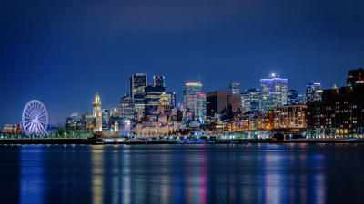 A night view of the illuminated skyline of Montreal from the Old Port, featuring the wheel.