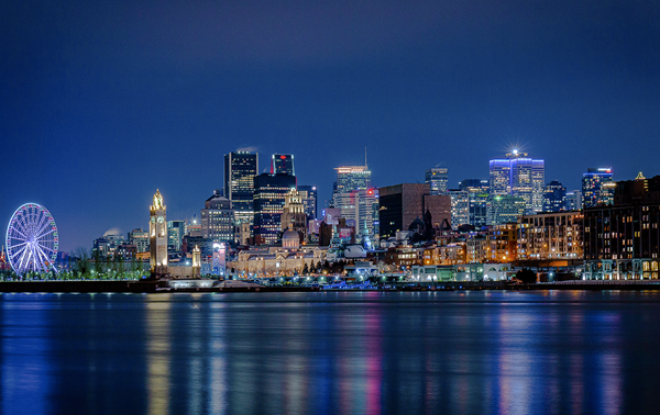 A night view of the illuminated skyline of Montreal from the Old Port, featuring the wheel.