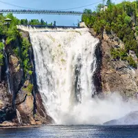 Chute Montmorency en été se jetant dans la rivière Montmorency en contrebas, entourée d'arbres avec une passerelle suspendue au-dessus
