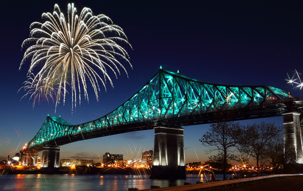 Jacques Cartier Bridge in Montreal at night, illuminated with fireworks overhead, overlooking the monument