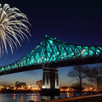 Jacques Cartier Bridge in Montreal at night, illuminated with fireworks overhead, overlooking the monument