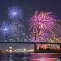 View of the clock tower and the Jacques Cartier Bridge in Montreal with fireworks overlooking the monuments